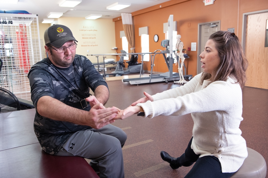 Physical therapists does PWR!Moves with client in the therapy gym.