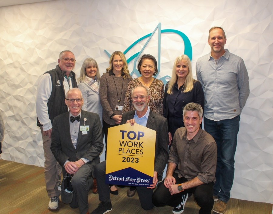 Origami Board Members hold the top workplaces sign and smile
