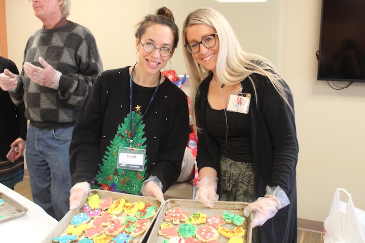Two happy volunteers decorate Christmas cookies.