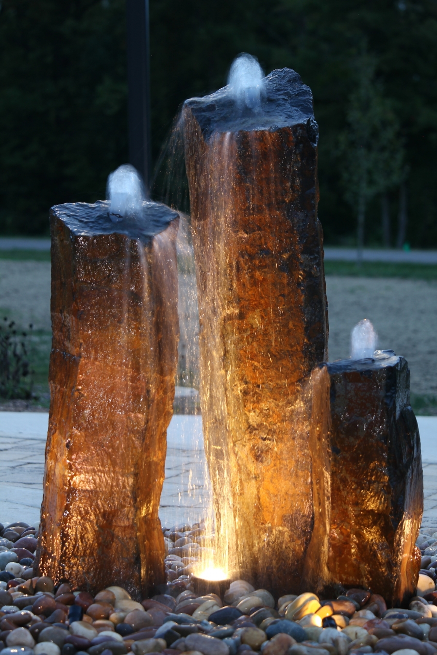 The beautiful water feature on Origami's campus is illuminated by light on a summer evening. 