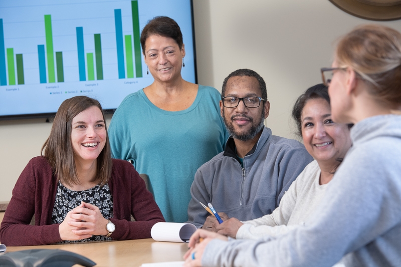 A group of clients and employees gather for a meeting in Origami's conference room.