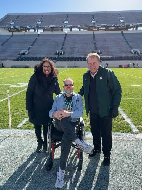 Tom and Lupe Izzo pause for a photo with an Origami resident on the MSU football field