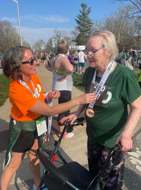 Origami resident receiving a metal from a volunteer