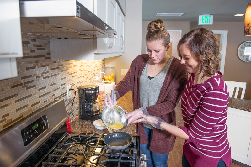 An Origami OT and client work on cooking skills in our assisted living home