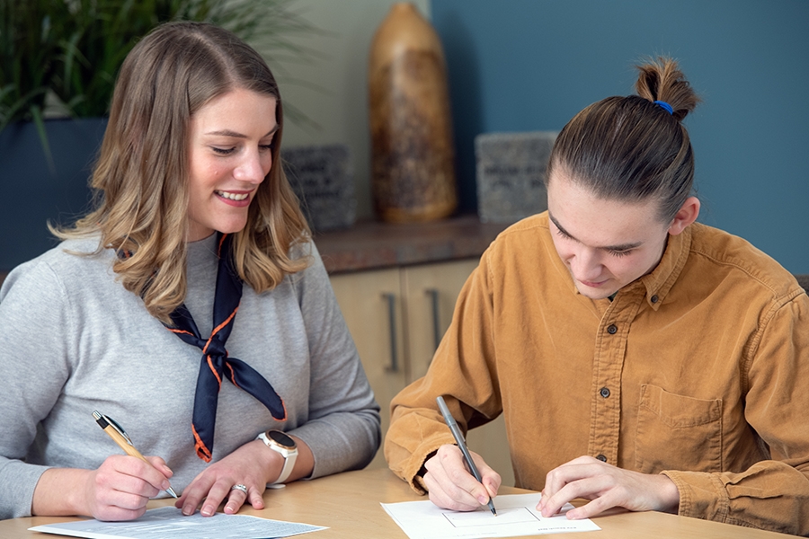 A staff member helps a client with writing.