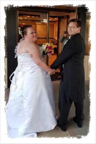 A bride and groom hold hands and look towards the camera