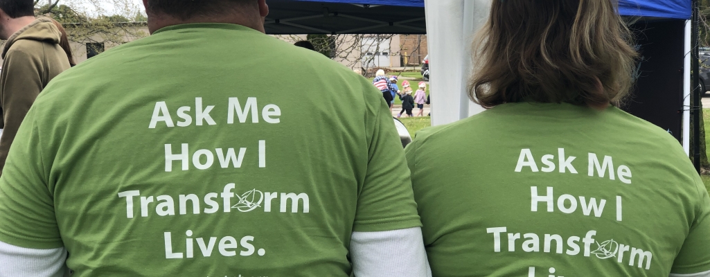 Two volunteers wear green Origami volunteer t-shirts.